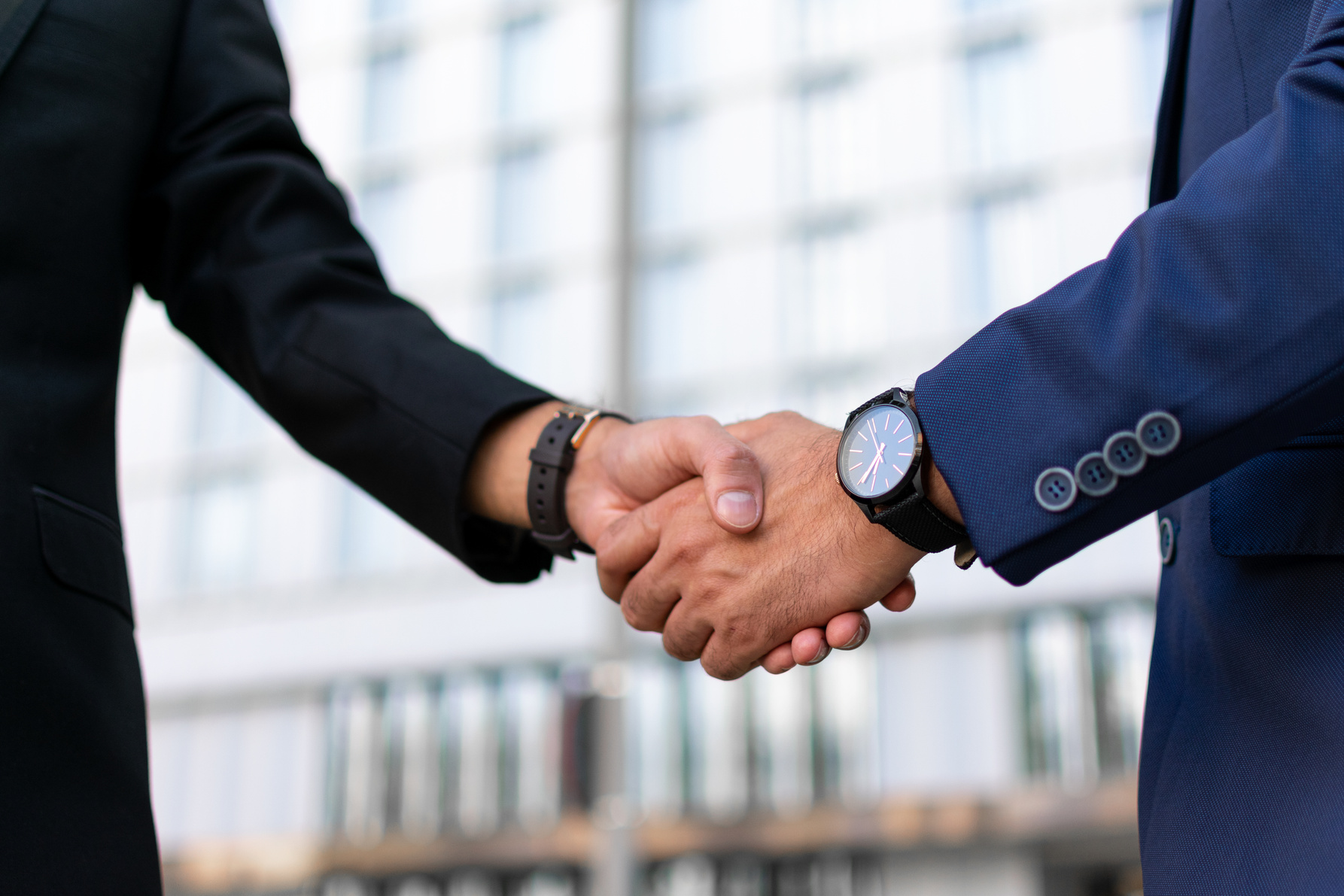 Partners greeting each other in business district. Business man and woman in office suits shaking hands outside. Handshake closeup concept